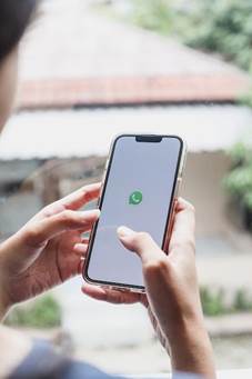 This may contain: a woman is holding her phone and looking at the whatsapp app on her screen